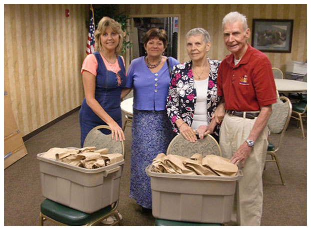 four people with two tubs of paper bags